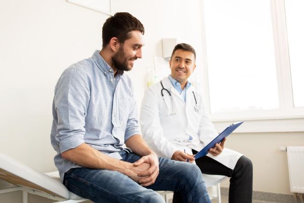 gooden-center-prescription-drug-addiction-photo-of-smiling-doctor-with-clipboard-and-young-man-patient-meeting-at-hospital