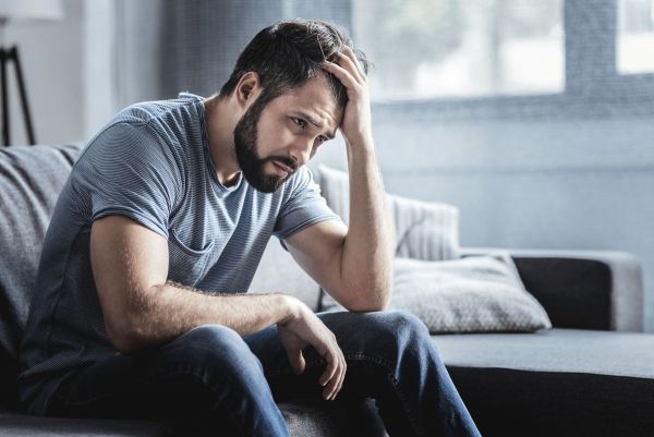 goodencenter-10-symptoms-of-depression-photo-of-a--Sad-unhappy-handsome-man-sitting-on-the-sofa