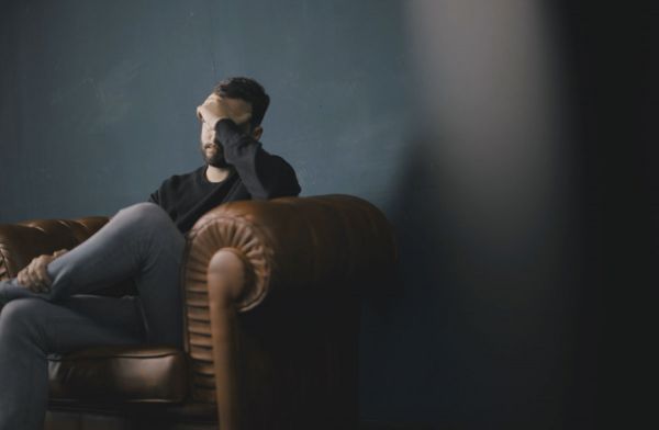 goodencenter-10-symptoms-of-depression-photo-of-a-man-sitting-on-sofa-against-wall