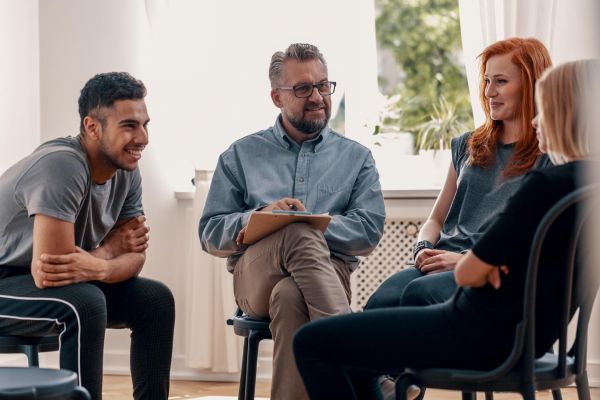 goodencenter-photo-of-Smiling-spanish-man-talking-to-his-friends-during-meeting-for-teenagers-with-therapist