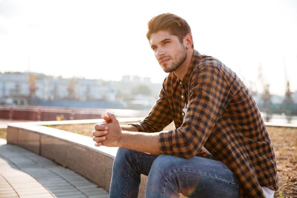 goodencenter-Sleep-and-Mental-Health-photo-of-a-Pensive-young-man-in-plaid-shirt-sitting-and-thinking-outdoors