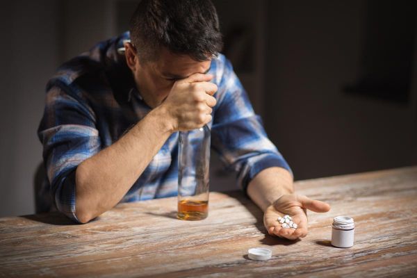 goodencenter-Why-Alcohol-and-Antidepressants-Should-Not-be-Mixed-photo-of-unhappy-drunk-man-with-bottle-of-alcohol-and-pills