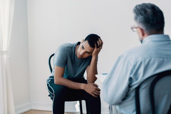 goodencenter-How-to-Live-with-Chronic-Pain-in-Recovery-photo-of-Depressed-teenager-looking-away-while-talking-to-his-therapist
