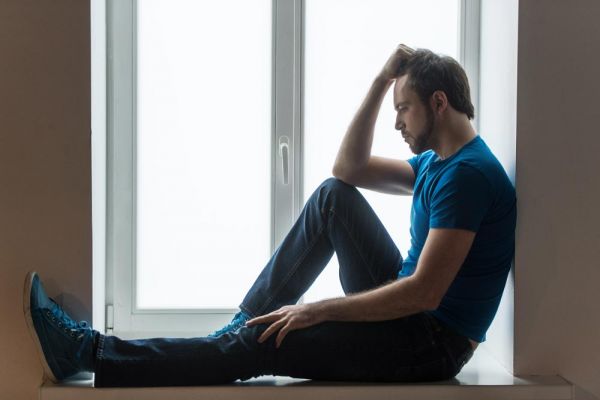 goodencenter-how-do-i-know-if-my-anxiety-is-serious-photo-of-a-Guy-holding-head-and-wearing-blue-shirt-and-jeans