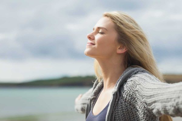 goodencenter-ten-Ways-to-Track-Your-Mental-Health-photo-of-a-young-woman-stretching-her-arms-on-beach