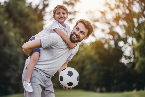 goodencenter-How-to-Maintain-Your-Mental-Health-over-the-Holidays-photo-of-a-father-and-son--having-fun-and-playing-football-on-green-grassy-lawn