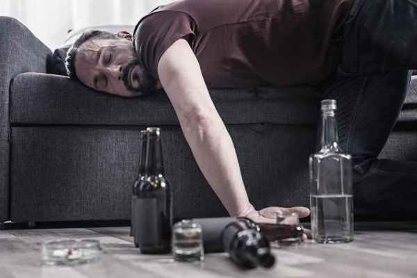 goodencenter alcohols effect on the body photo of a Drunk bearded adult man lying on the sofa