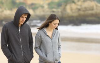 woman together with a loved-one struggling with addiction walking on the beach