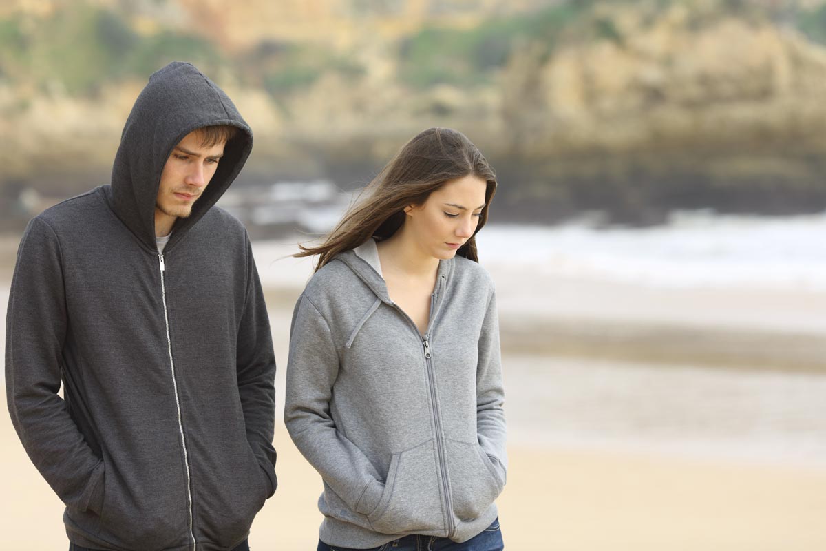 woman together with a loved-one struggling with addiction walking on the beach