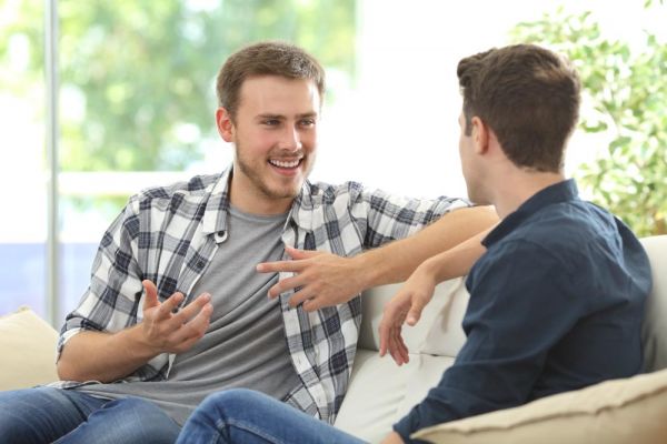 Two friends talking sitting in a couch inside the workplace