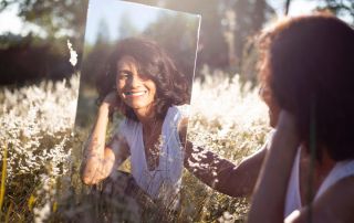 a photo of a woman with mental health disorder sitting on the grass looking at the mirror, narcissism