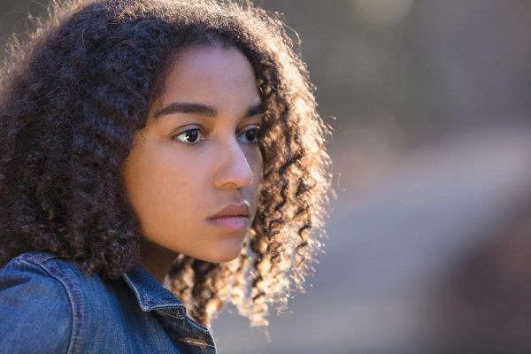 photo of a beautiful mixed race African American girl teenager female young woman outside by a road looking sad depressed or thoughtful