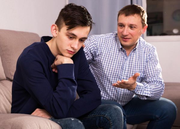 photo of a teenager offended and father is asking for his forgiveness at the home