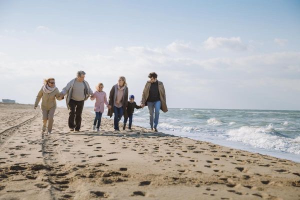 Photo of big multigenerational family walking together on beach at seaside after attending a family therapy